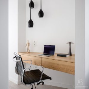 Studio in casa con scrivania sospesa in legno e sedia ergonomica in ecopelle nera con ruote